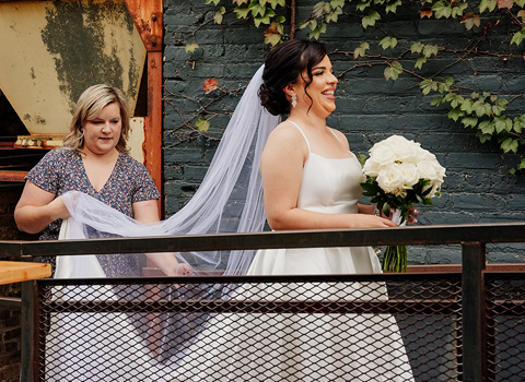Liza Loret Founder helping bride with veil during a photo shoot.