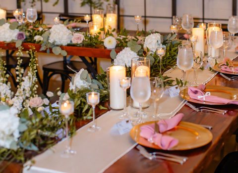Candles and plates on a table at a wedding reception.